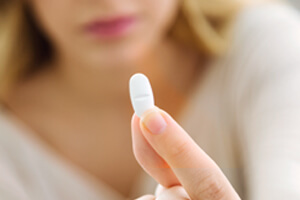 woman holds up white Percocet thinking if needs a residential rehab facility